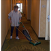 Worker using the Bissell BG102 Upright Vacuum to clean the floor in a commercial setting.
